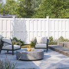 White vinyl privacy fence behind a backyard fire pit and two chairs