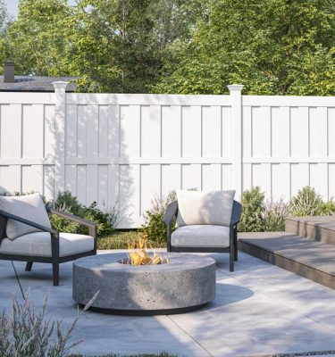 White vinyl privacy fence behind a backyard fire pit and two chairs