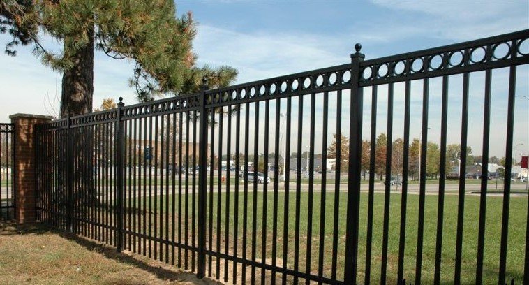 Black aluminum fence with decorative tops along a field