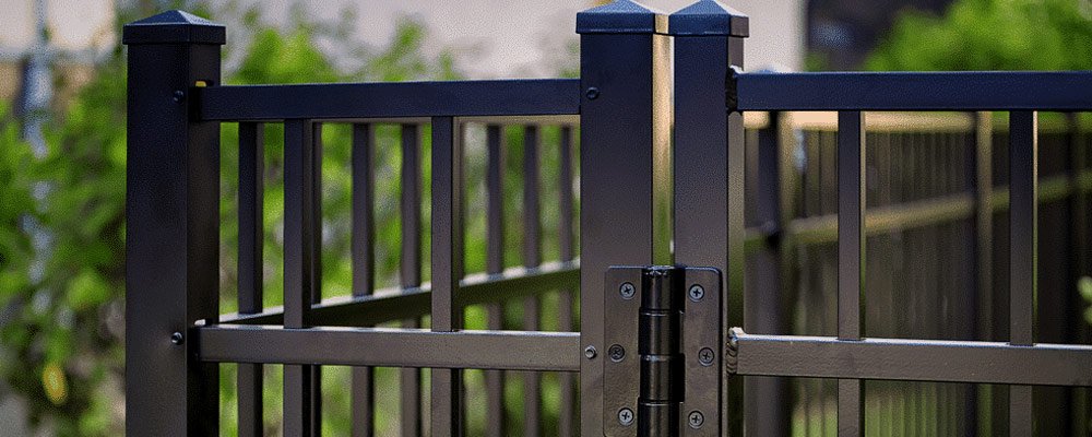 Close-up of a black aluminum picket fence rail and post