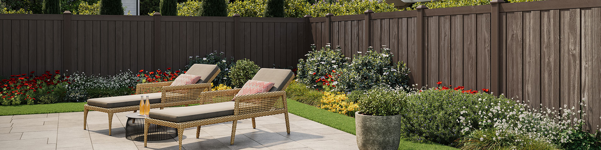Woodgrain molded composite fence behind two lounge chairs in a landscaped garden