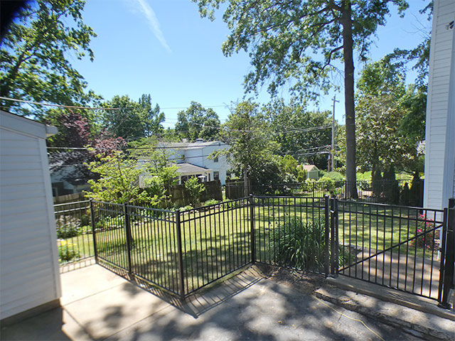 Black aluminum fence enclosing the backyard in Brentwood, MO, mounted to the patio near the deck stairs