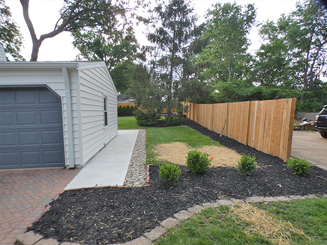 Backyard in Kirkwood, MO with a wood privacy fence along the back line and the driveway side open, before the aluminum gate was installed