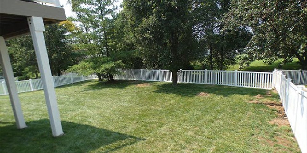 White vinyl fence enclosing a grassy backyard beside a deck