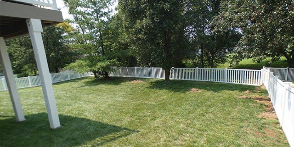 White vinyl spaced picket fence along a backyard lawn at a home in Imperial, MO