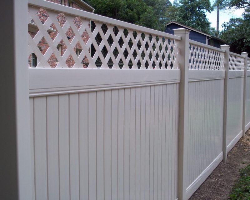 Almond-colored vinyl privacy fence with a lattice top over solid panels