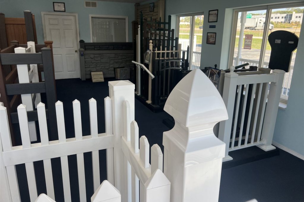 White fence with rounded-top pickets and a gate on display in the Arnold showroom